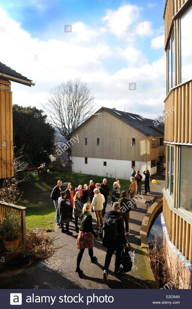 Modern cohousing community with shared courtyard and residents socializing outdoors