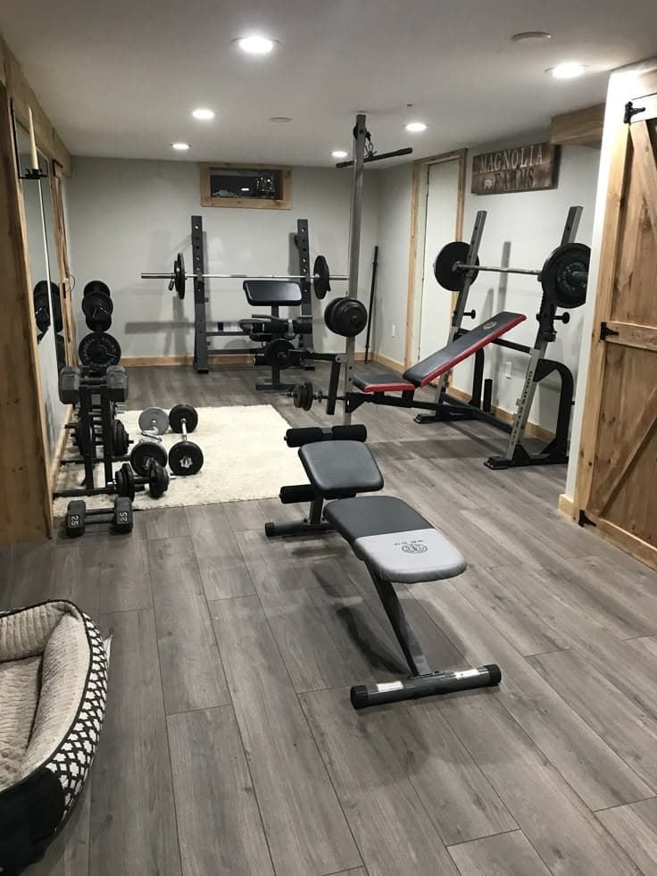 Home gym setup with dumbbells and a barbell rack in a garage