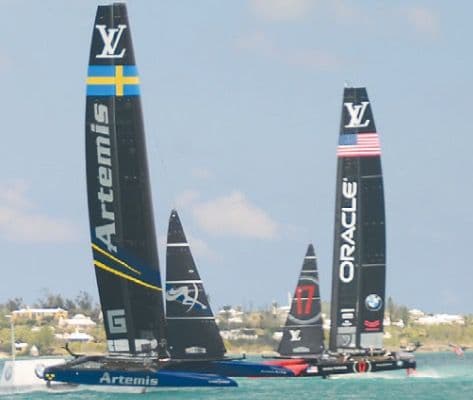 Racing sailboat cutting through blue ocean water with sails raised