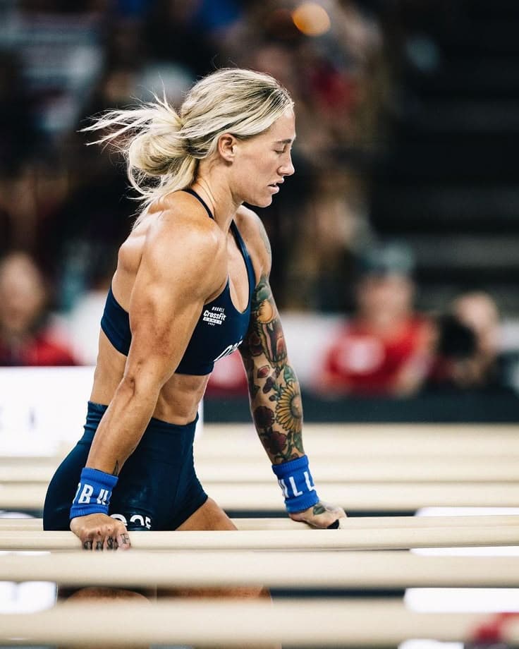 Athletes competing in a CrossFit workout with barbells and gymnastics rings