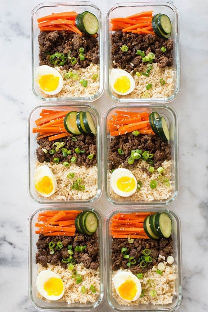 Rows of meal prep containers filled with portioned food on a kitchen counter
